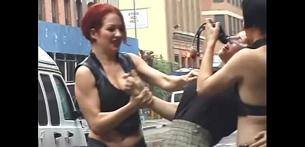  Two lustful lesbians tie their redhead girlfriend to a pole on the street and beat her with a whip